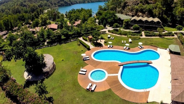 Un complexe hôtelier doté d’une grande piscine de forme irrégulière, entourée de chaises longues et d’une terrasse en bois.
