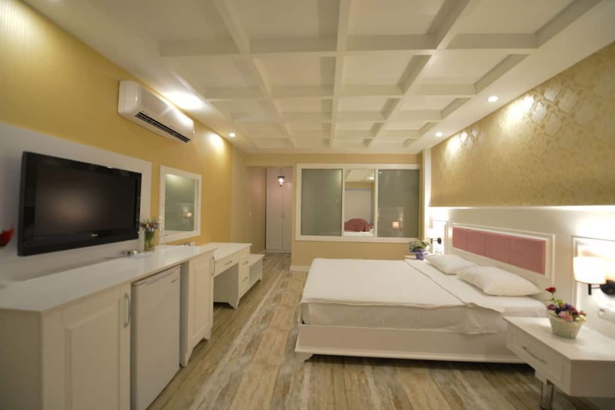 A hotel room with a bed, bedside table, TV, and a bathroom with a mirror and sink.