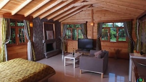 L’intérieur d’un chalet en bois chaleureux et accueillant, avec une cheminée, un téléviseur, un canapé et un lit.