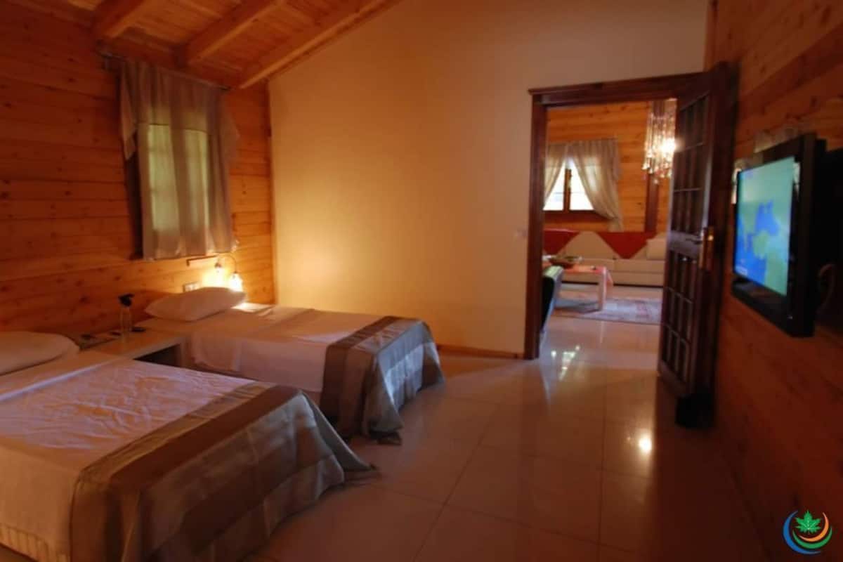 A wooden cabin with two single beds, a TV, and a small dining area.
