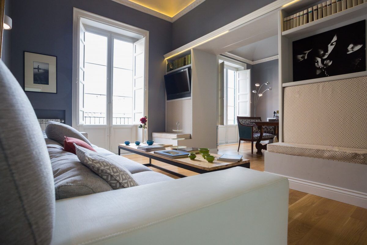 Un salon moderne avec un canapé, une table basse et un téléviseur. On y trouve également des étagères et un tableau accroché au mur.