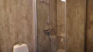 A bathroom with a toilet, a shower with a glass door, and a tiled floor.
