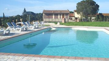 Una piscina al aire libre, sillones reclinables de piscina