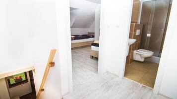 A bedroom with a bed, a small window, and a bathroom with a toilet and sink.