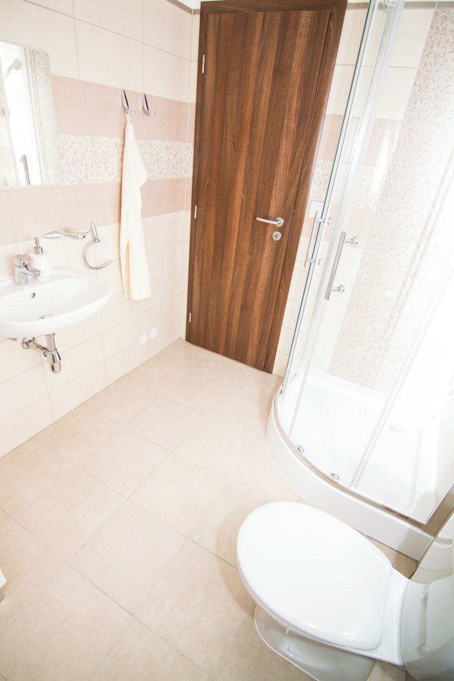 A bathroom with a white sink, a toilet, and a shower enclosure.