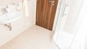 A bathroom with a white sink, a toilet, and a shower enclosure.