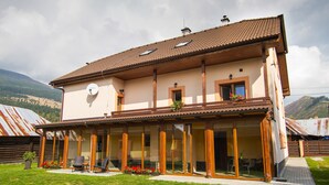 Una casa de dos pisos con balcón, ventanas grandes y una antena parabólica.
