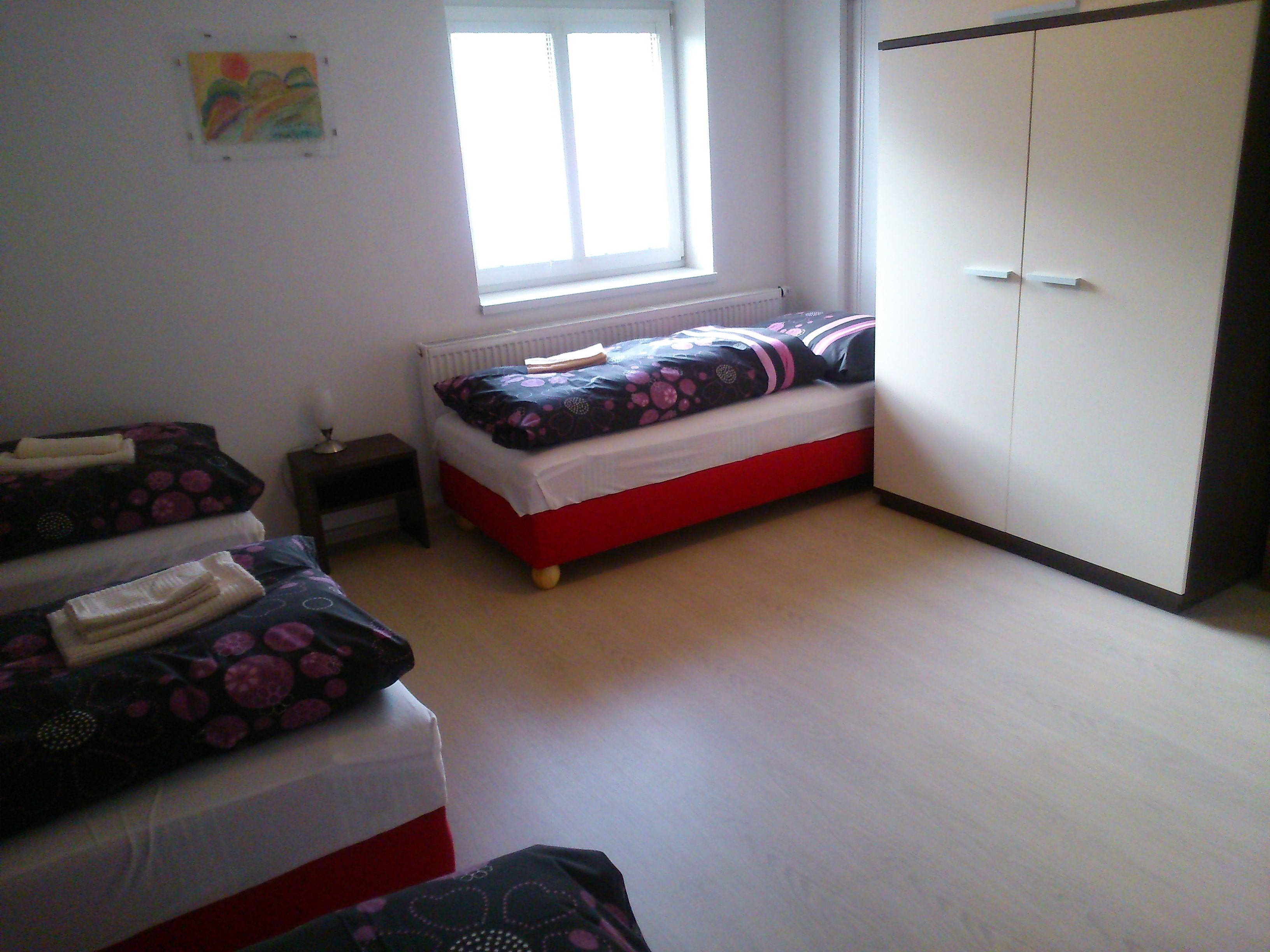Un dormitorio con una cama individual, un armario y una mesita de noche pequeña.