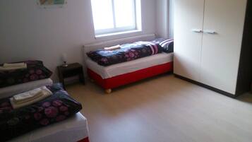 Un dormitorio con una cama individual, un armario y una mesita de noche pequeña.