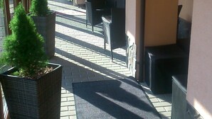 Un espacio al aire libre cubierto con suelo de ladrillo, plantas en macetas y mobiliario exterior.