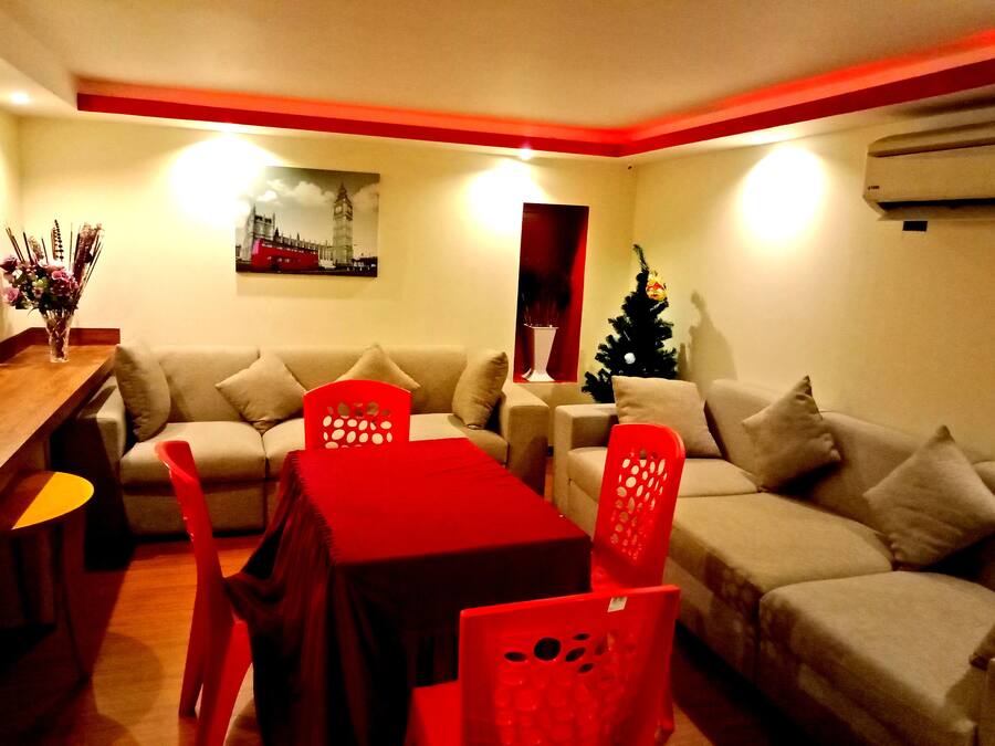 A living room with a sofa, a dining table with chairs, a Christmas tree, and a painting of a cityscape.