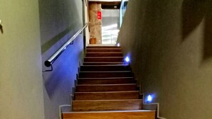 Un escalier en bois, doté d’une rampe, qui mène à un ascenseur.