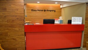 Un comptoir d’accueil de l’hôtel Easy Hotel à Ampang, avec un mur en bois en arrière-plan et un comptoir rouge.