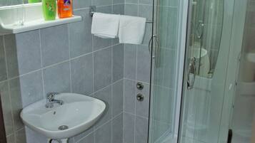 Une salle de bain équipée d’un lavabo, d’une douche à parois de verre et de toilettes.