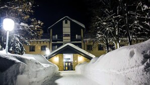 Sendero cubierto de nieve que lleva a un hotel con una entrada destacada y una señal.