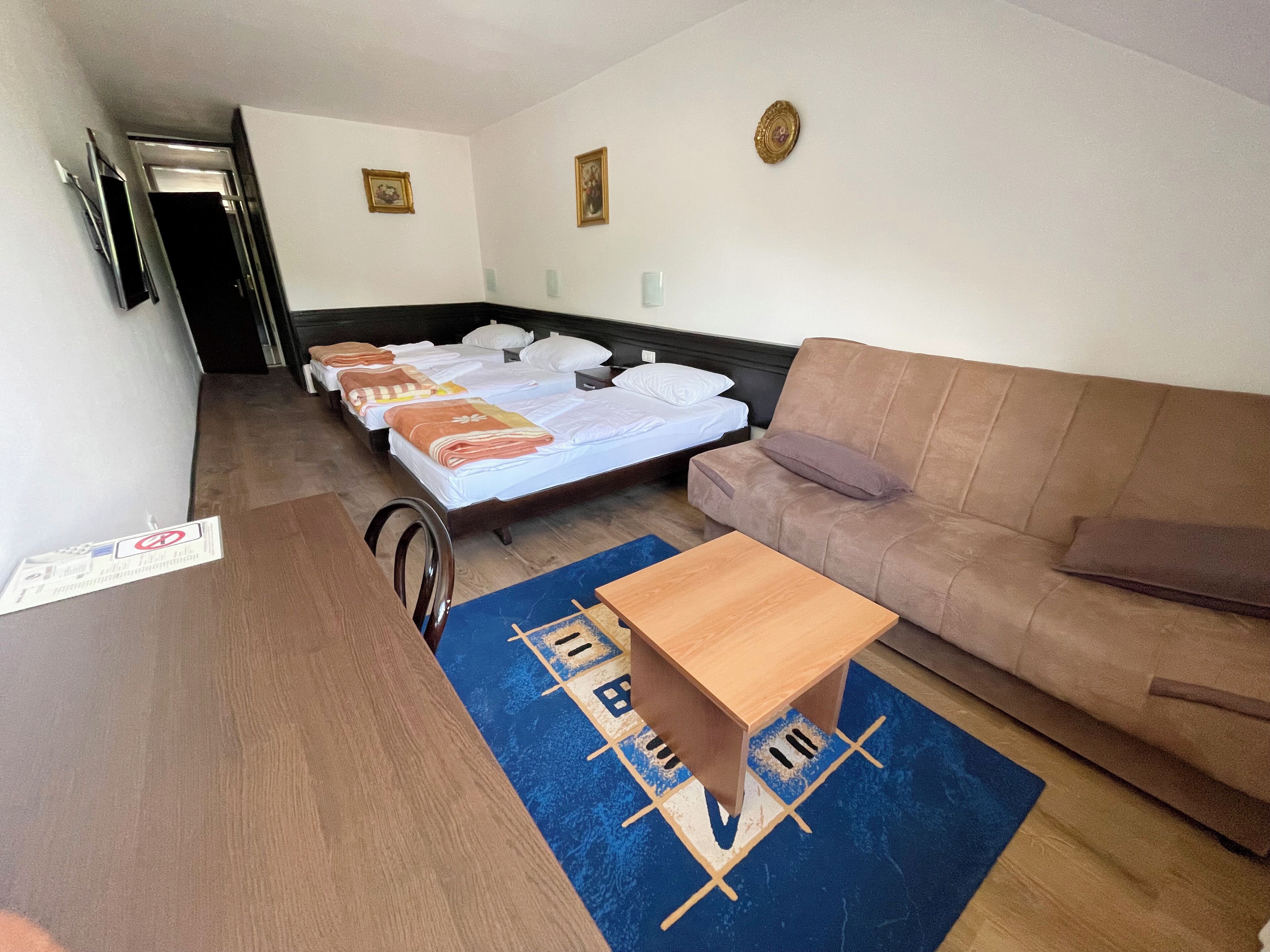 Una habitación de hotel con una cama, un sofá, una mesa de madera y una alfombra azul.