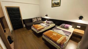A room with two beds, a sofa, a door, and a painting on the wall.