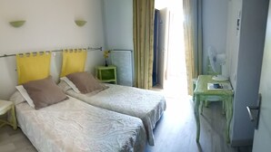 A bedroom with two beds, a small table, a chair, and a radiator. - Hotel La Font de Lauro (Saumane-de-Vaucluse)