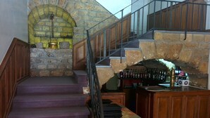 Un escalier menant à une arche en pierre, un coin bar avec des bouteilles et une rambarde en bois.