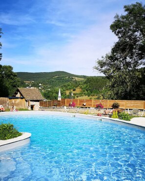 Une piscine avec, en arrière-plan, un bâtiment dont le toit est fait de chaume.