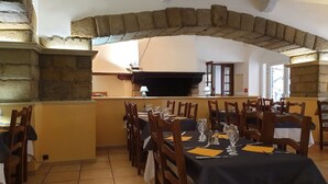 Un restaurant doté d’arches en pierre, de tables et de chaises en bois.