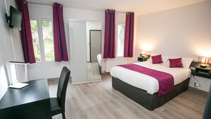 Une chambre d’hôtel avec un lit, un bureau, une chaise, une télévision et des rideaux.