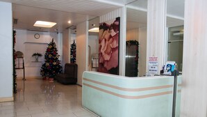 Un espace d’accueil avec un sapin de Noël, un comptoir de réception et une horloge au mur.
