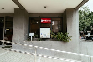 A RedDoorz building with a glass entrance and a signboard advertising various services.