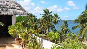 A thatched-roof structure with a view of the sea and palm trees. - Pwani Guest House (Lamu)