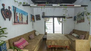 A cozy room with two sofas, a bed, and a window with curtains. - Pwani Guest House (Lamu)