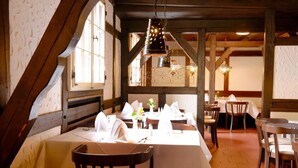 A restaurant with wooden beams, white tablecloths, and hanging pendant lights. - Hotel Restaurant zur Linde (Pattensen)
