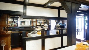 A bar area with wooden beams, shelves of bottles, glasses, and a white counter. - Hotel Restaurant zur Linde (Pattensen)
