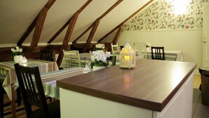 A dining area with a wooden table and chairs, a lantern, and floral decorations. - Hotel Kungsängstorg (Uppsala)