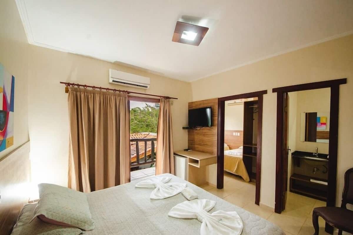 Hotellihuone, jossa on sänky, työpöytä, televisio ja kylpyhuone.