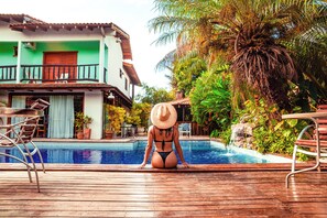 A person sitting by a pool with a house in the background. - Pousada Chamamé (Bonito)