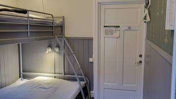 A bunk bed with a ladder, a white door with a sign, and a wooden floor.