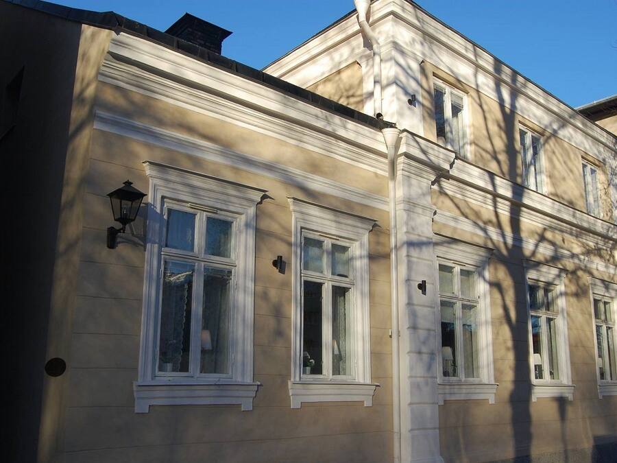 Un bâtiment doté de nombreuses fenêtres et d’un lampadaire, présentant un style architectural classique avec une conception symétrique et des éléments décoratifs blancs.