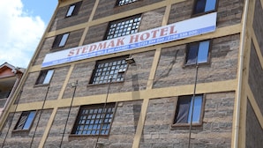 Un edificio de varios pisos con un cartel que indica 'STEDMAK HOTEL', señalando que ofrece alojamiento de lujo con servicio de desayuno incluido.