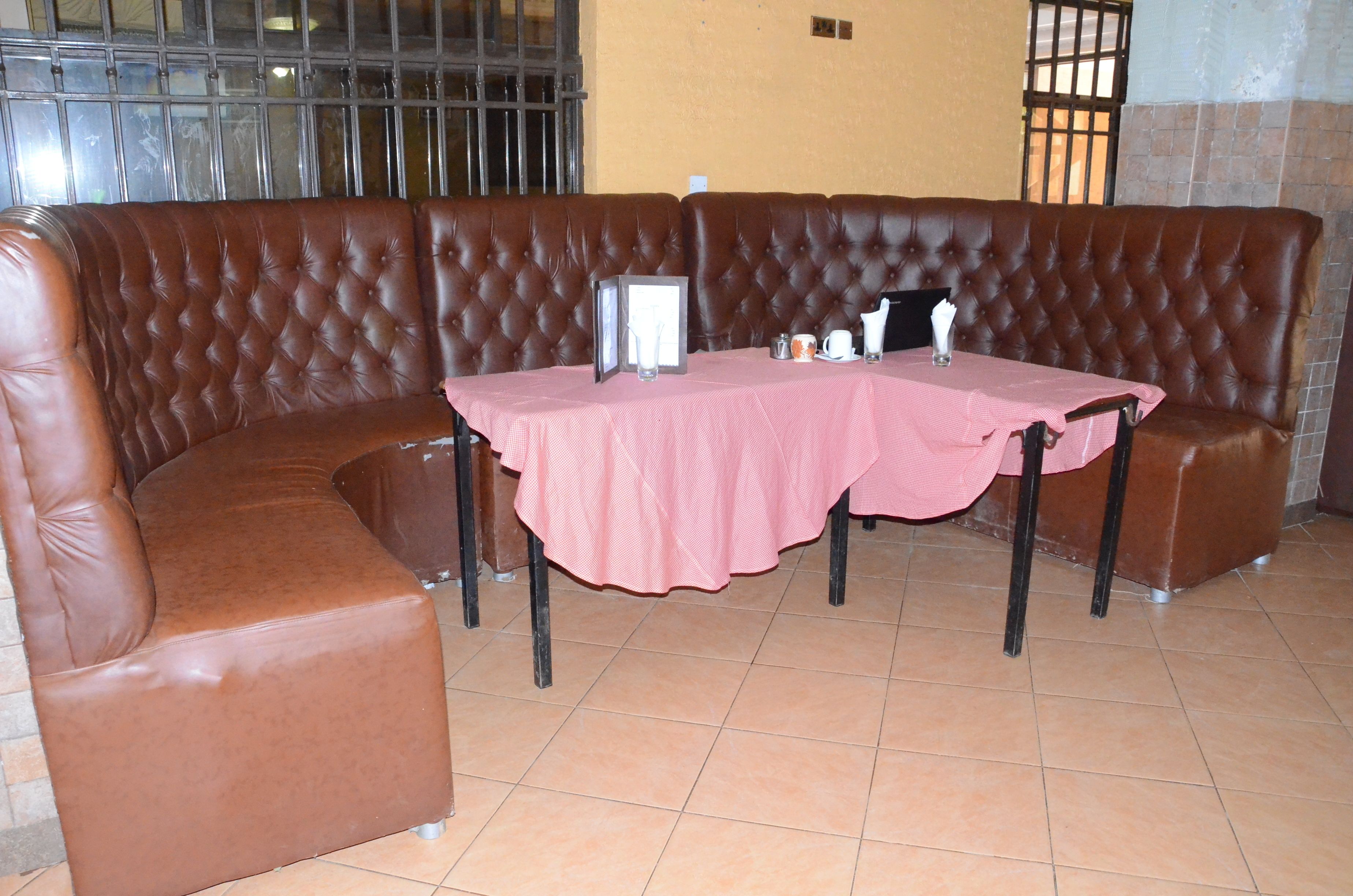 A corner booth with a pink tablecloth, leather seating, and a small table with a pitcher, cup, and saucer.