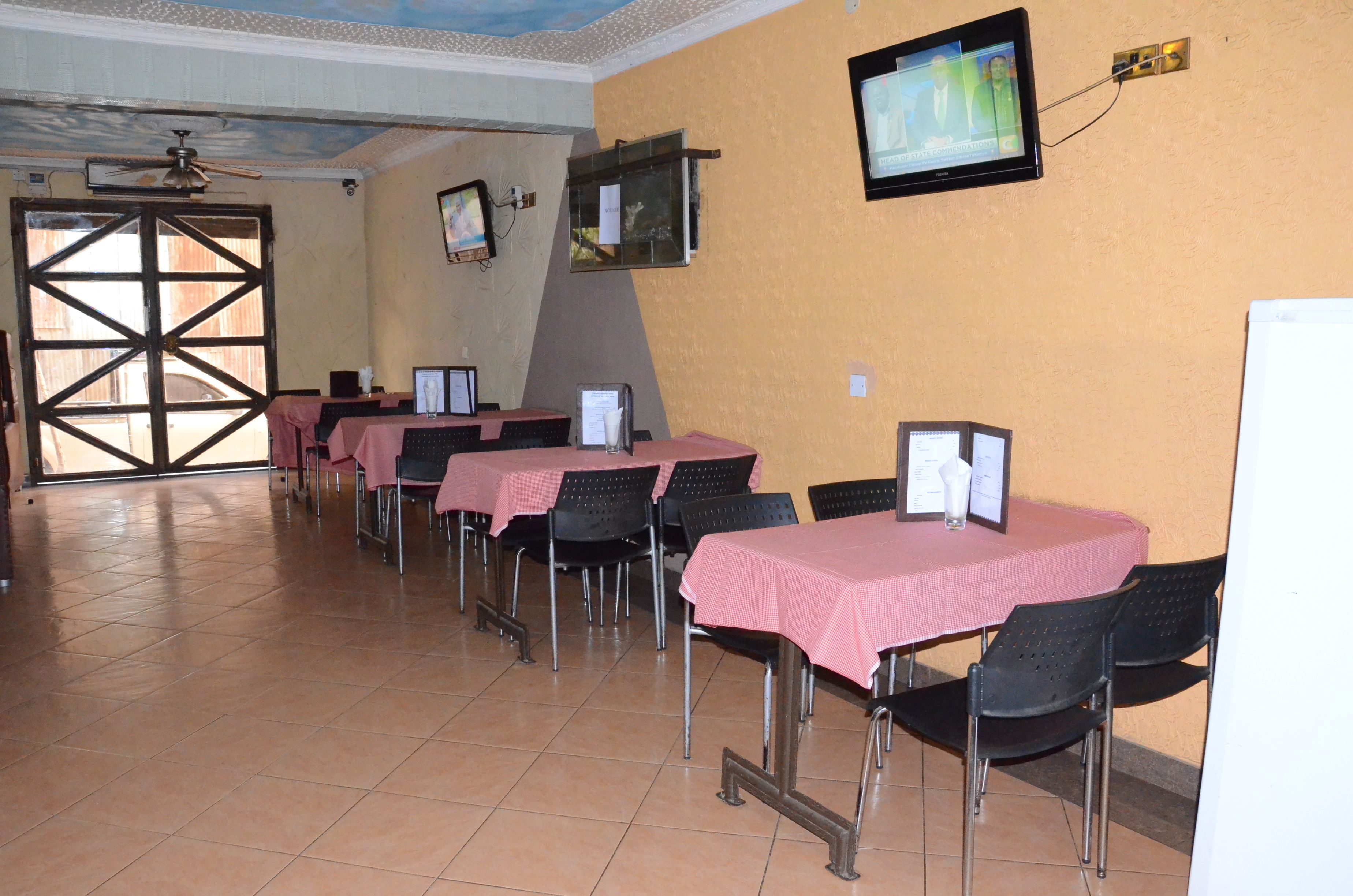 A conference room with tables and chairs, a ceiling fan, and a television screen.