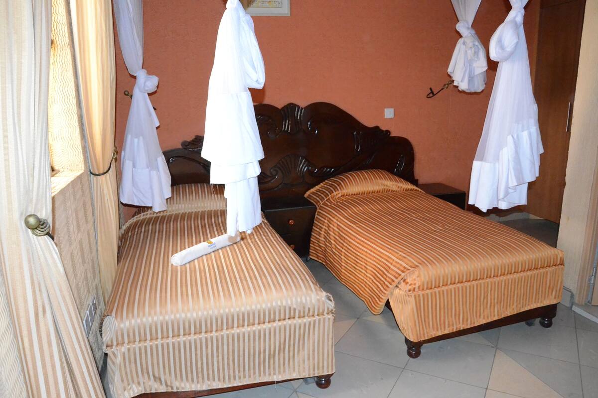 A room with two beds, each with striped bedding, a wooden headboard, and a nightstand.