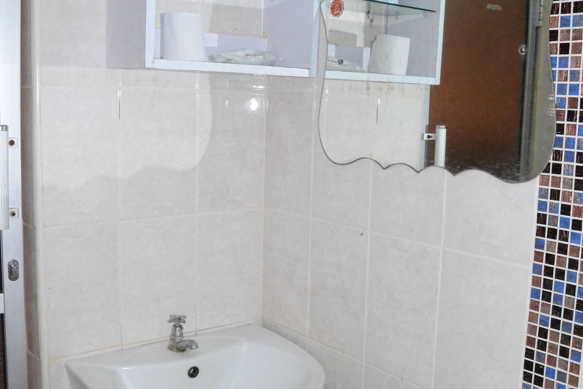 A bathroom with a pedestal sink, a toilet, and a glass-fronted medicine cabinet.