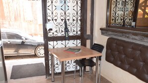 Un rincón pequeño y acogedor con una mesa y sillas, una ventana con detalles de hierro forjado y una puerta que da al exterior.