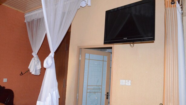 Un dormitorio con una cama, un televisor montado en la pared y una puerta con vidrio esmerilado.