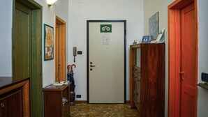 A narrow hallway with a tiled floor, a door with a green sign, and wooden doors on either side. - Bed&Breakfast Arcobaleno (Bologna)