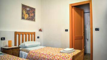 Een slaapkamer met twee bedden, een houten hoofdbord, een aan de muur hangend schilderij en een deur naar een andere kamer.