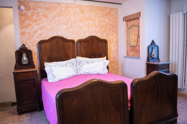 A bedroom with a wooden bed, a nightstand, a dresser, and a mirror on the wall.