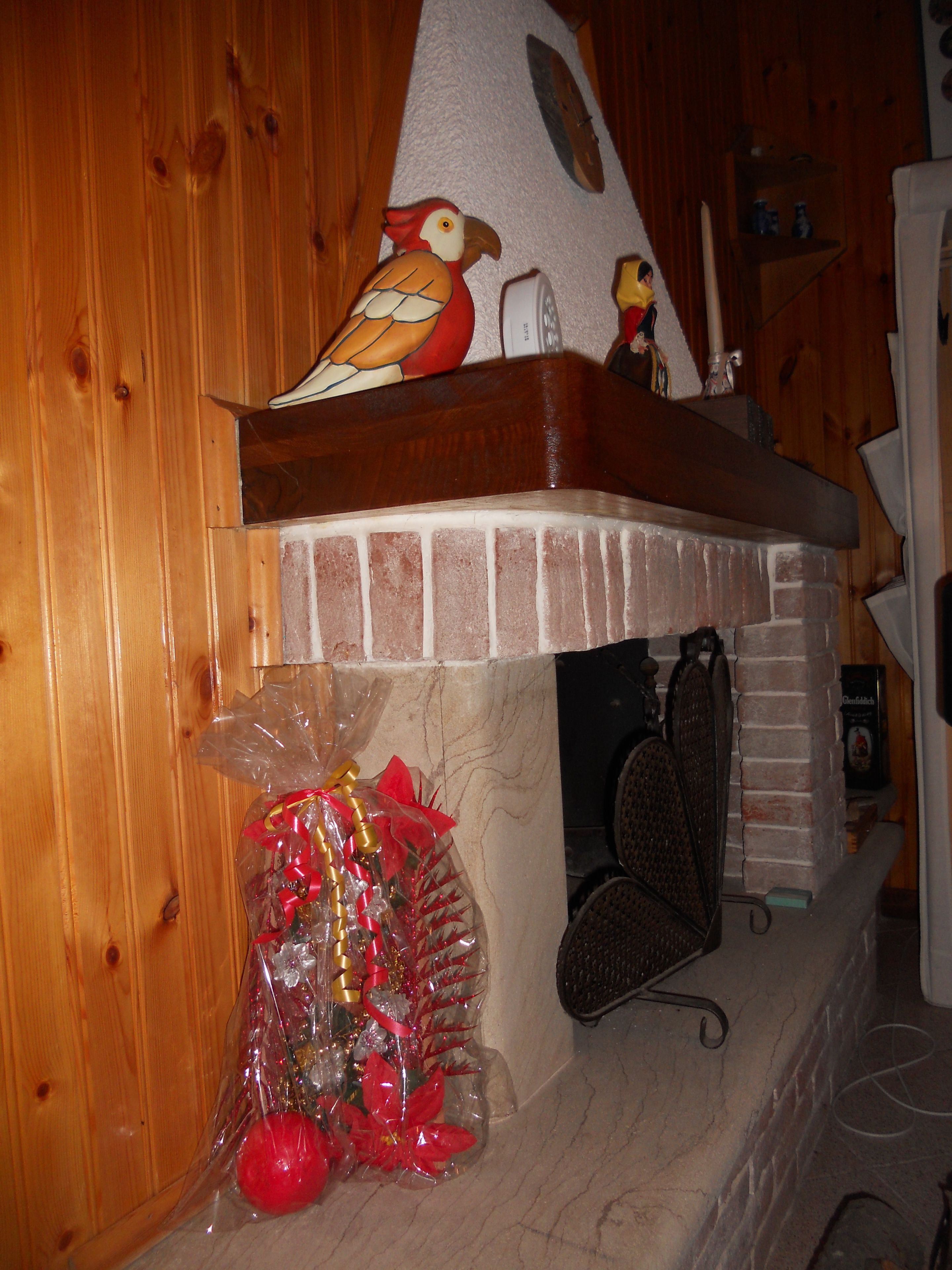 Un interior de madera con chimenea, un pájaro decorativo y una bolsa de regalo.