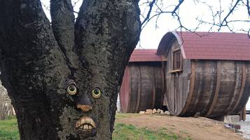 Ein Baum mit einer geschnitzten Gesichtszug, eine Holzhütte mit rotem Dach und ein Erdreich.