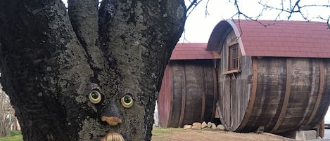 A tree with a carved face, a wooden structure with a red roof, and a dirt ground.